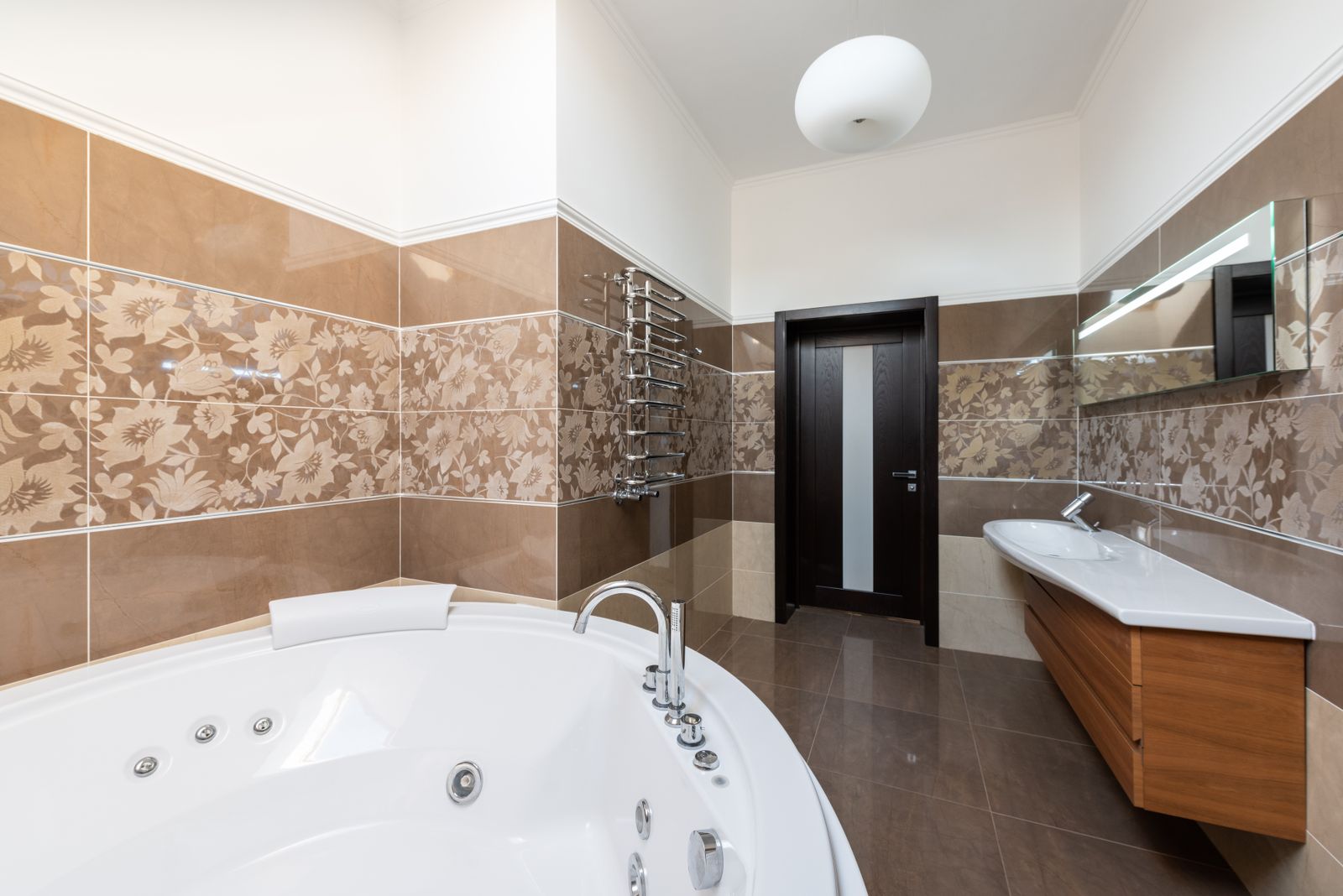 A bright, modern home bathroom with a bath, sink and wooden cabinet.