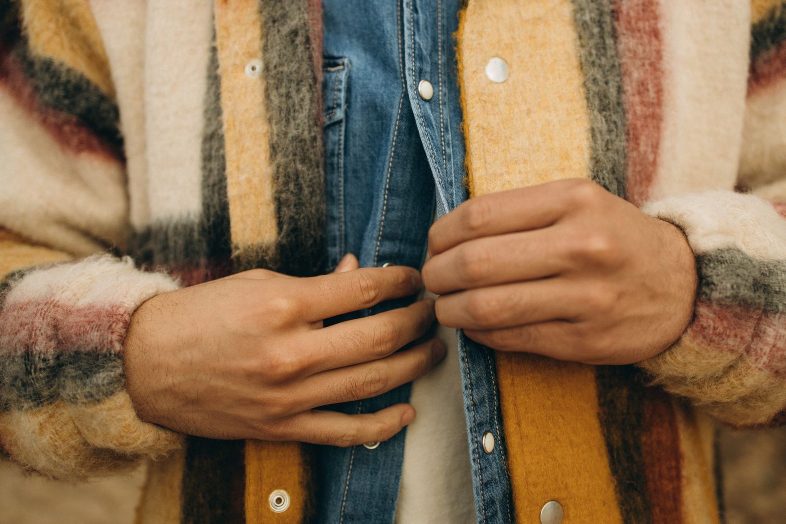 Close-up of a person's hands doing up the buttons of a shirt.