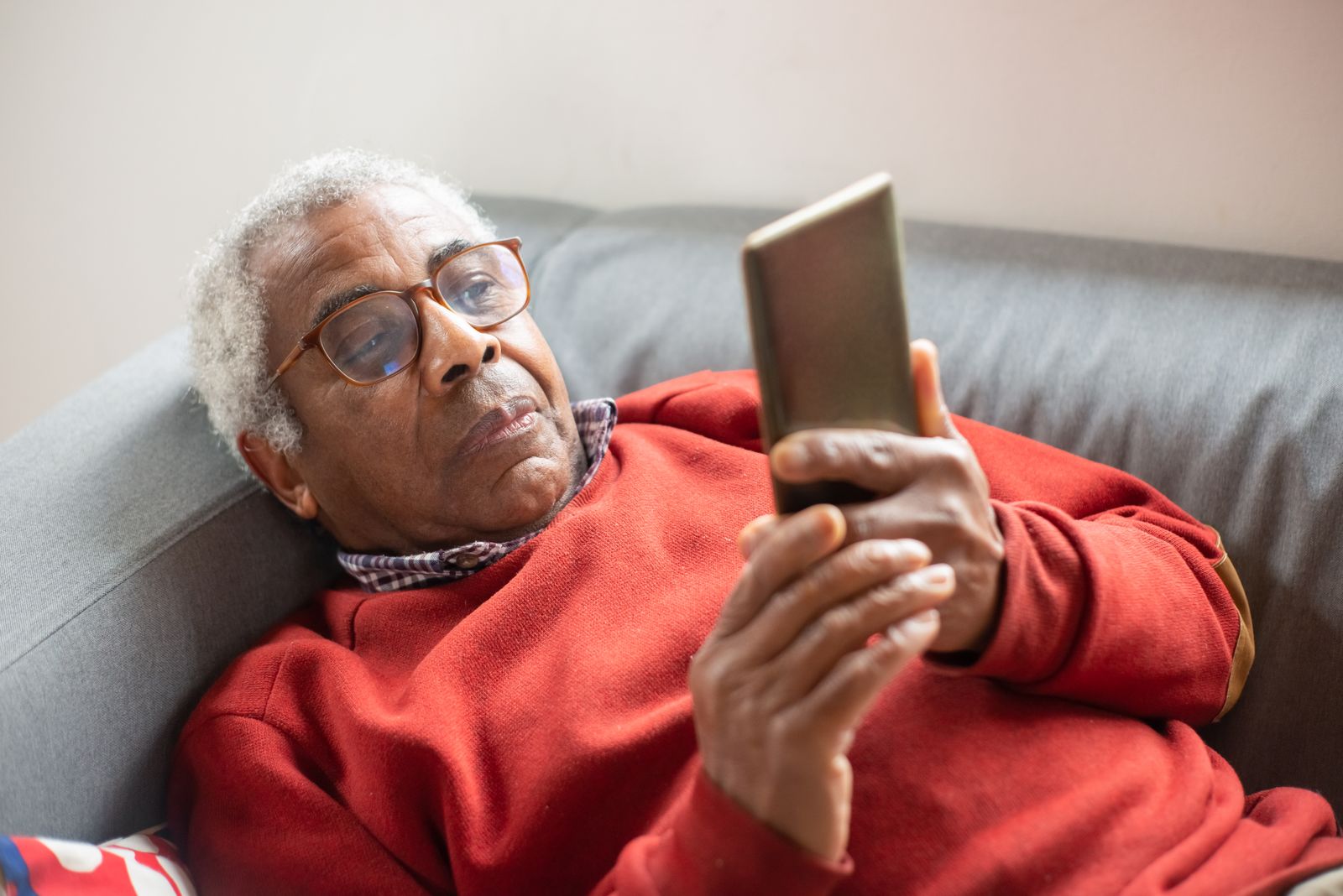 An older man wearing glasses using a mobile phone at home.