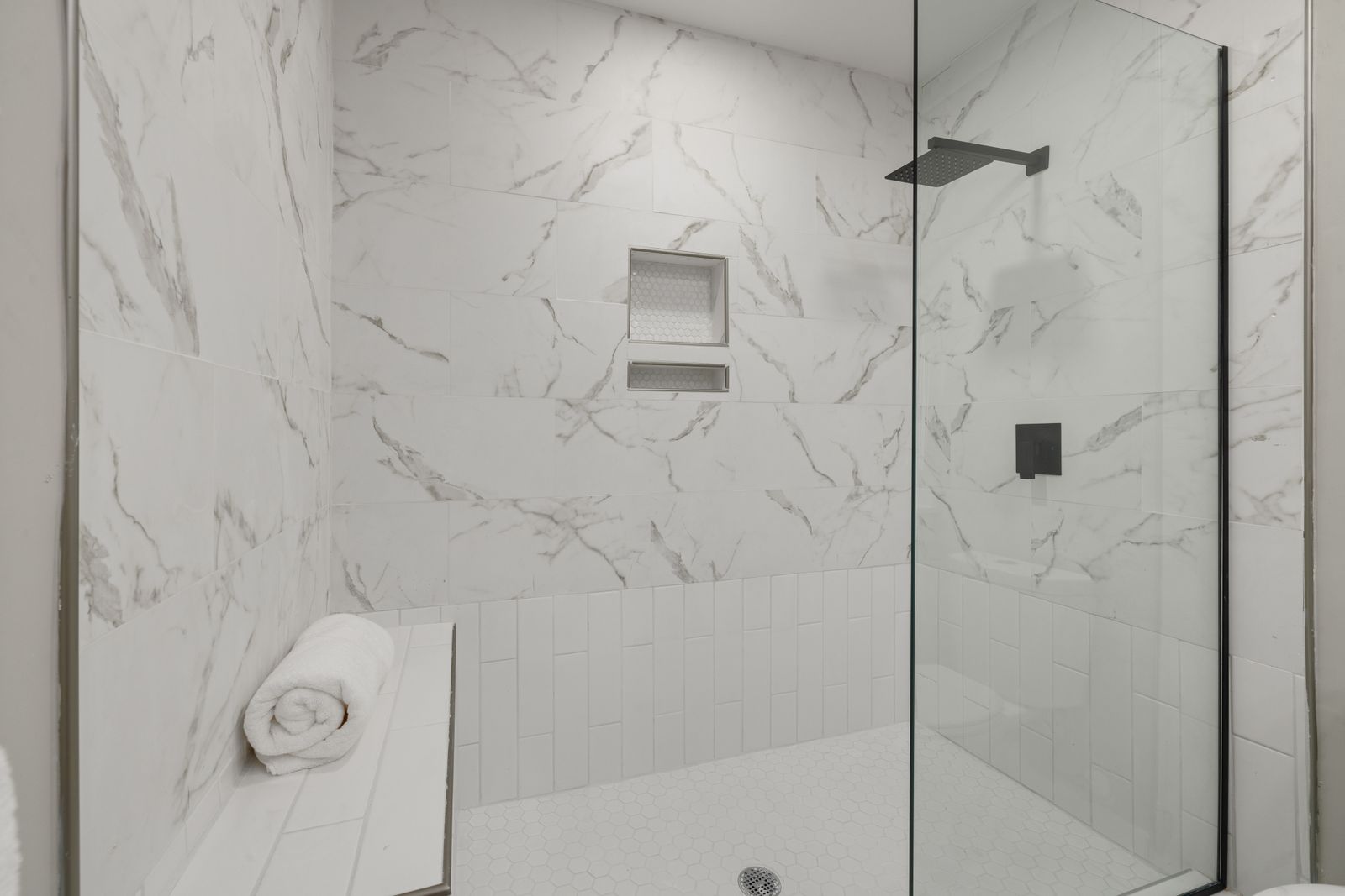 A modern walk-in shower with a built-in bench seat.