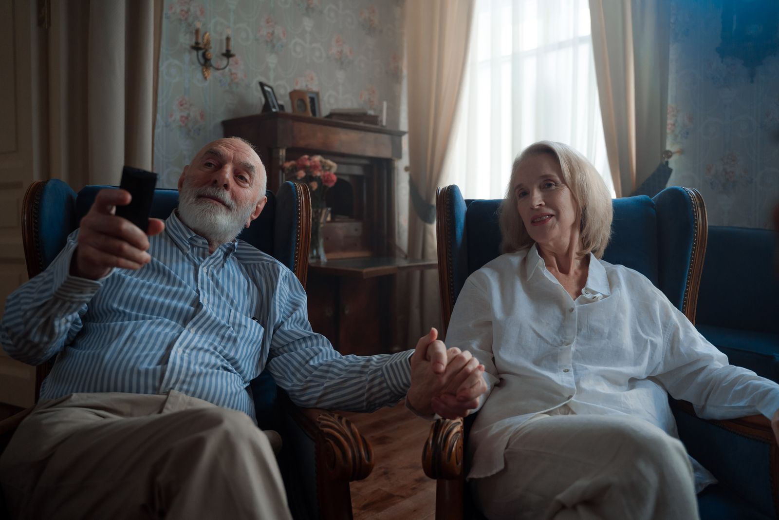 An older couple sitting together watching television in a cosy living room.